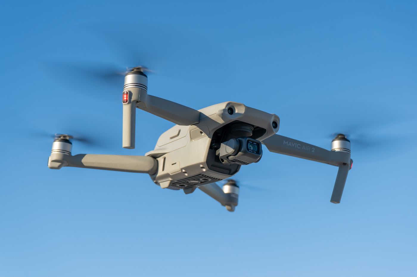 Camera-equipped surveillance drone in flight against a clear sky